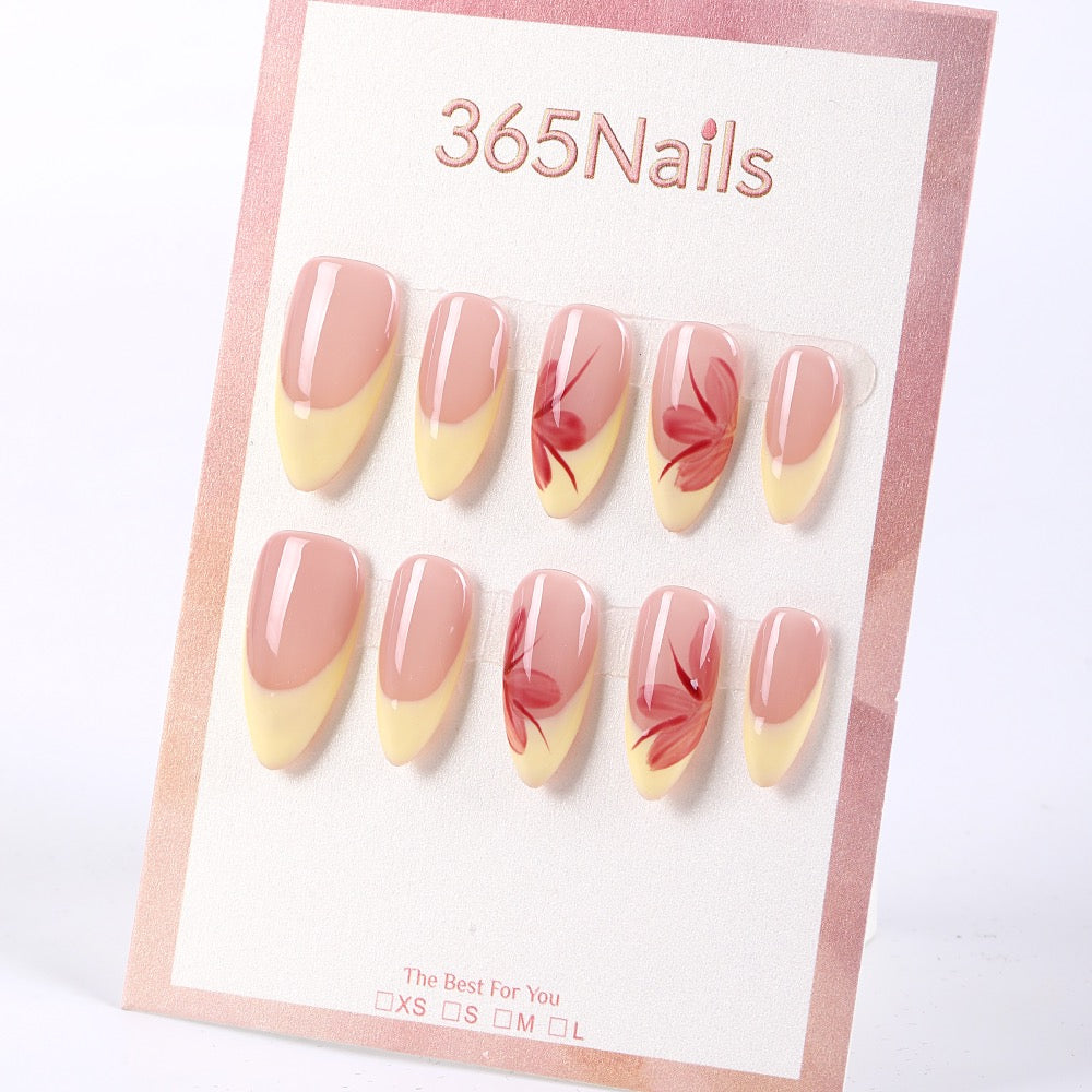 Uñas postizas almendradas 365nails con base color nude, francesa amarillo mantequilla y flores pintadas a mano.