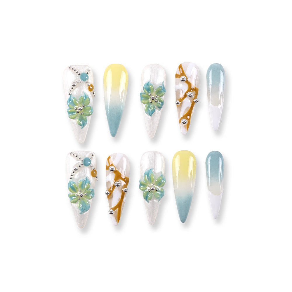 Uñas postizas 365Nails color blanco lechoso estilo francés con degradado azul menta y limón, flores 3D y cuentas plateadas.