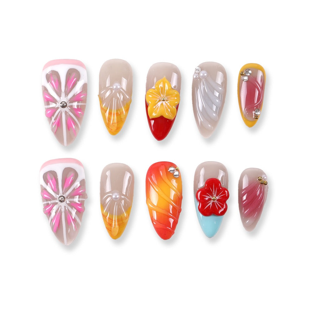 Uñas postizas 365Nails con base color gris lechoso y degradado de gelatina color atardecer, flores 3D, tallado ondulado y detalles de cristal.