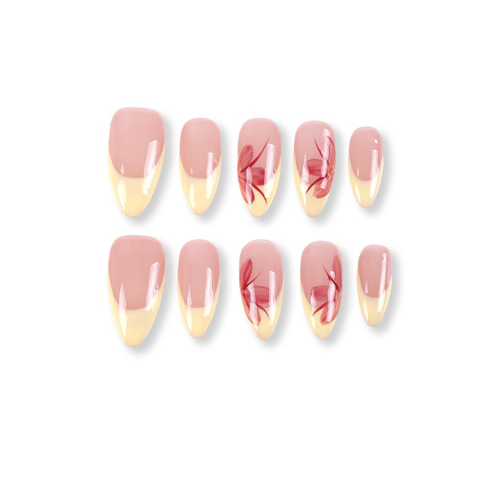 Uñas postizas almendradas 365nails con base color nude, francesa amarillo mantequilla y flores pintadas a mano.