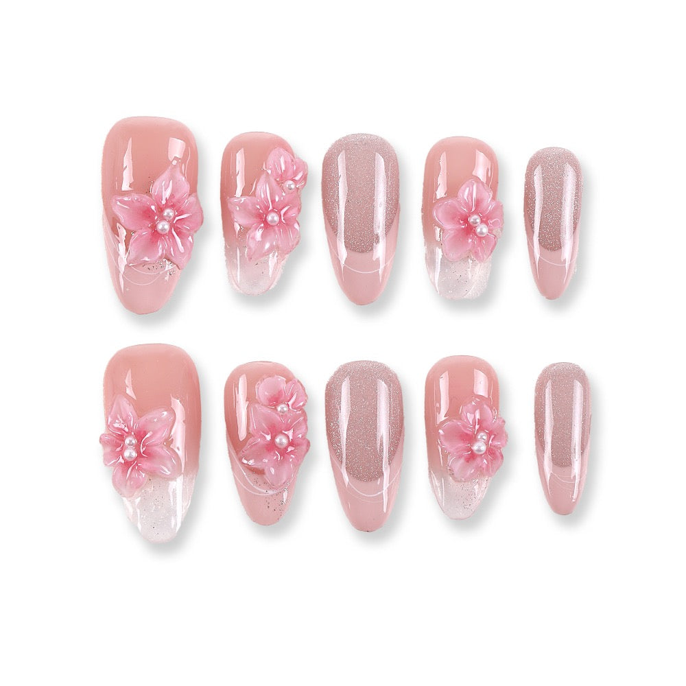 Uñas postizas almendradas largas 365Nails color pétalo de rubor con flores 3D y purpurina azucarada.