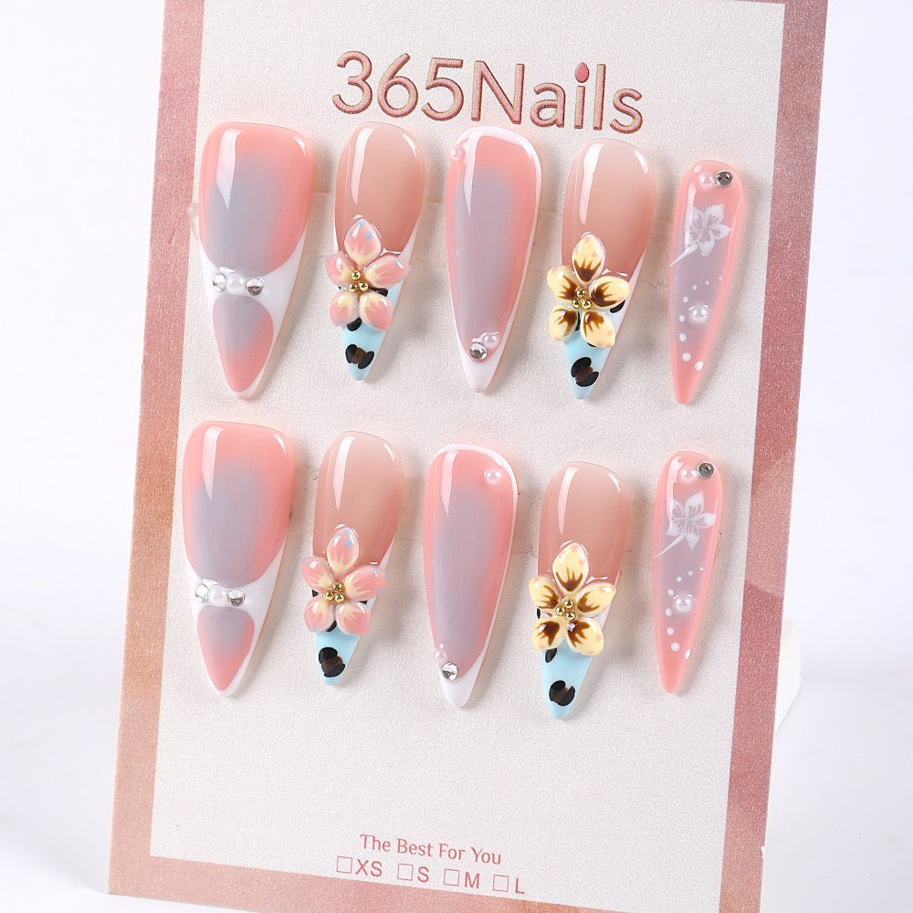 Uñas postizas 365Nails color nude-coral gris degradado con flores doradas 3D y detalles de perlas francesas.
