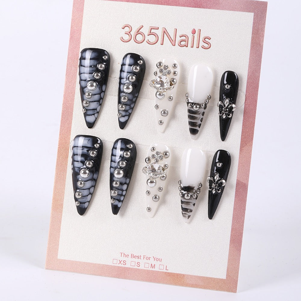 Uñas postizas de estilete con diseño de mármol blanco y negro de 365Nails con dijes de pedrería.