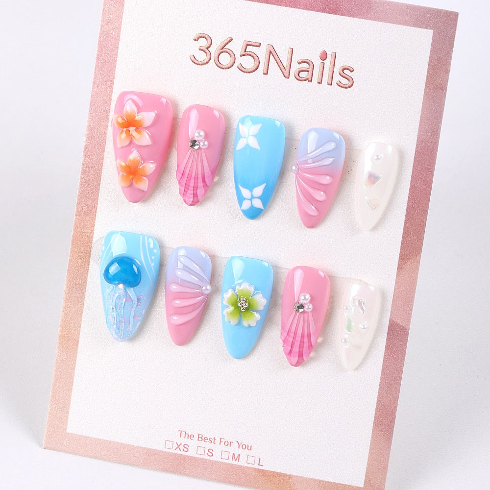 Colorful press-on nails with seashell, blossom, and rhinestone designs on a light background, representing the variety of styles available from wholesale suppliers.