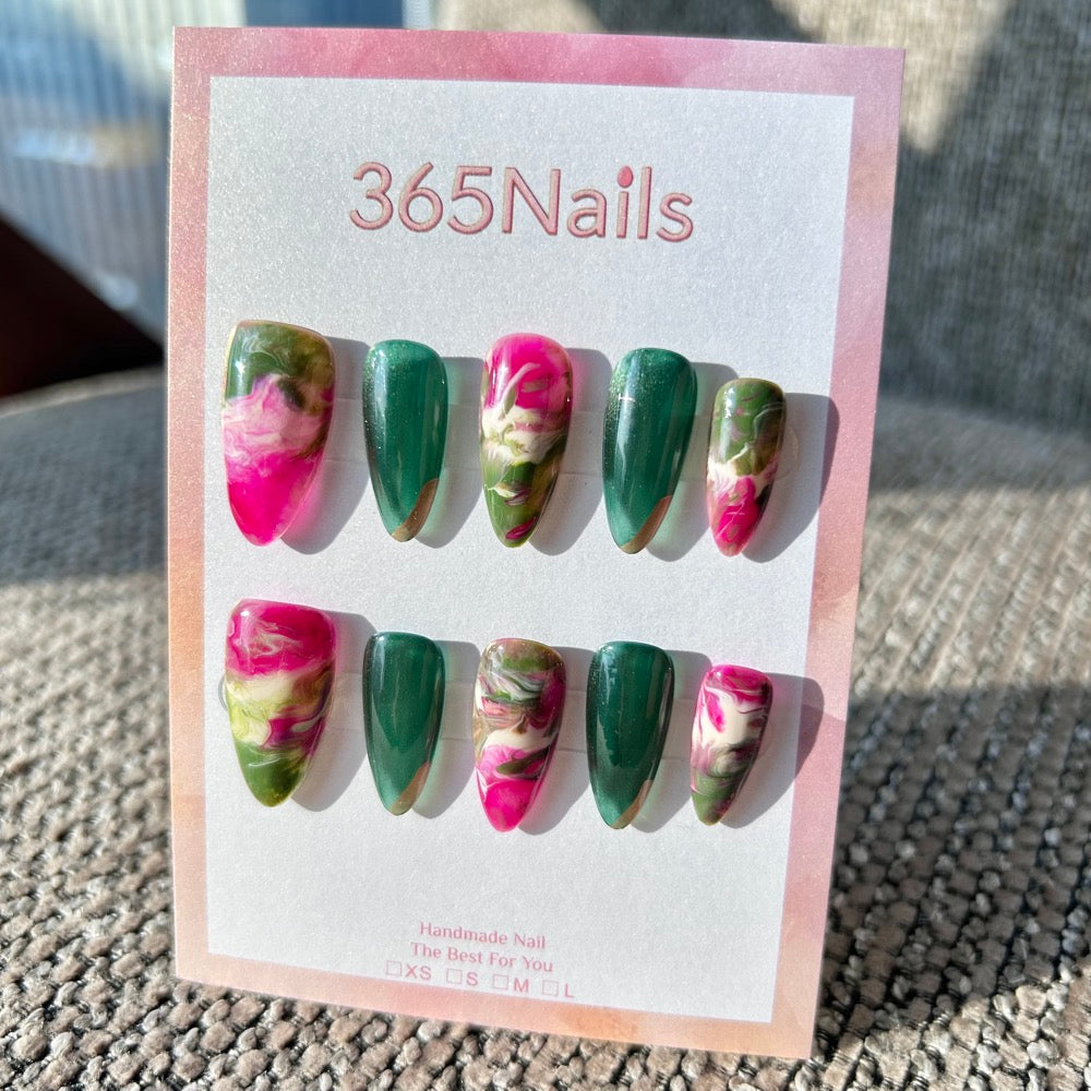 Ecommerce workspace with three press-on nail sets in branded packaging, sample notes, and a laptop showing product listings.