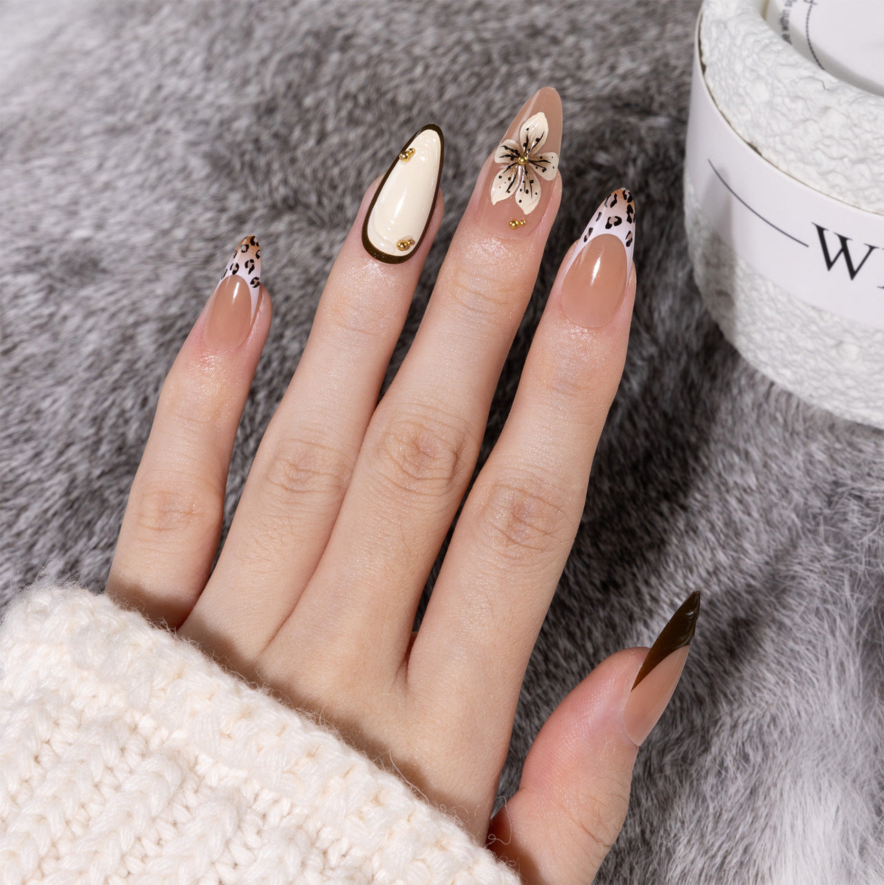 Hands demonstrating trimming and fitting press-on nails using adhesive tabs and a file on a clean white work surface