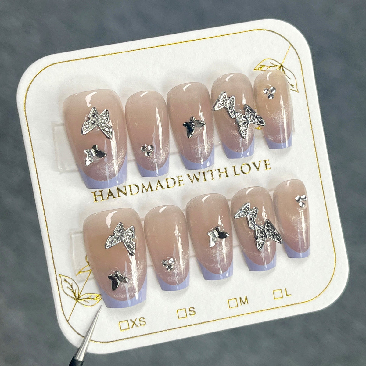 Nude nails with lavender French edges and silver butterfly decorations