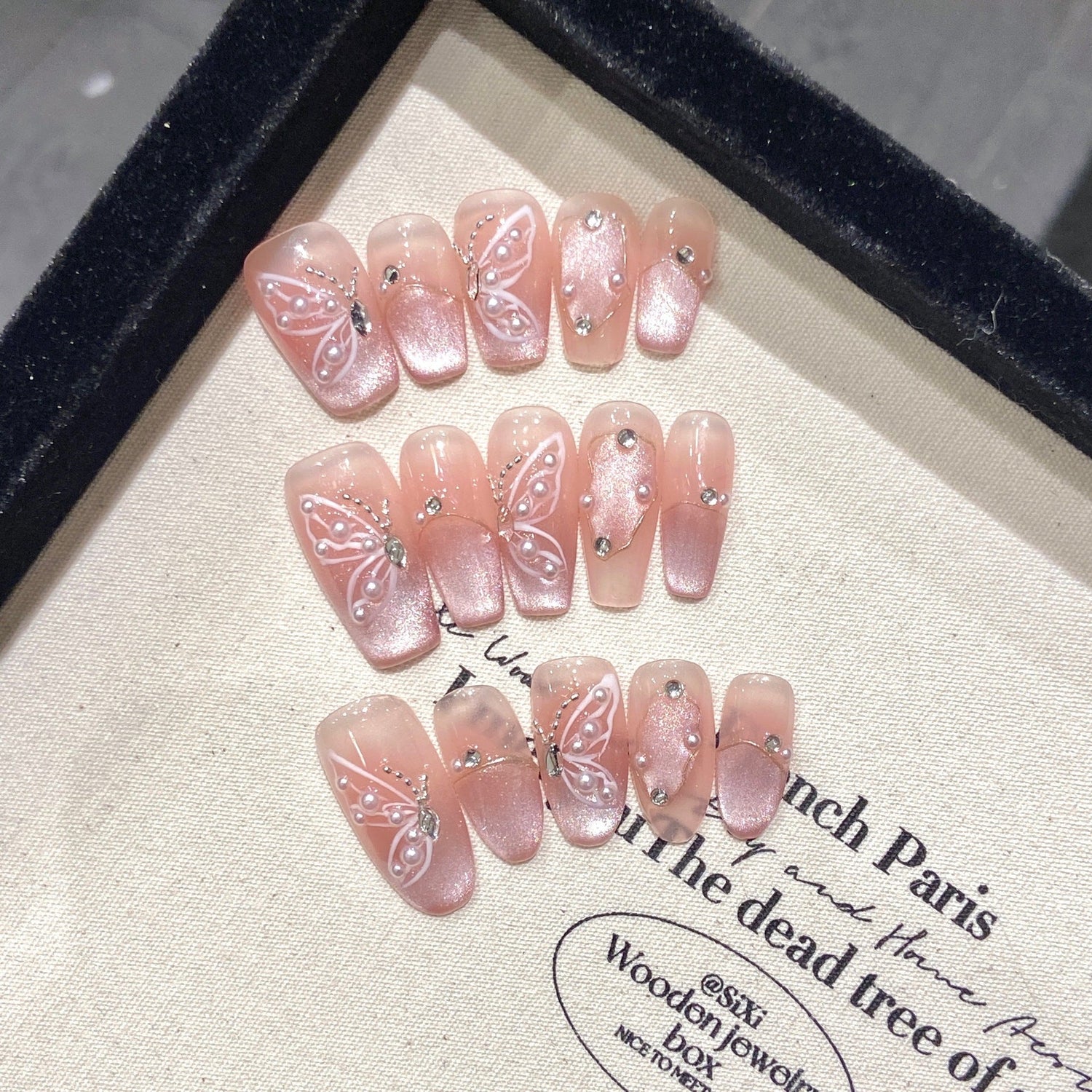Handmade press-on nails featuring a 3D butterfly and cat eye design on almond shape, demonstrating detailed craftsmanship for quality control evaluation.