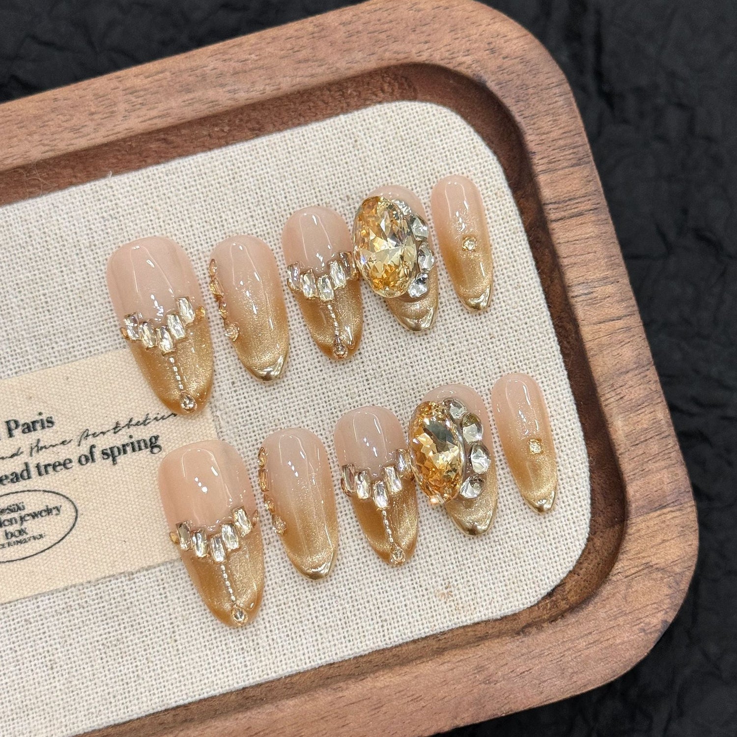 Champagne Luxe custom press-on nails with cat eye magnetic effect, gold crystal details on almond shape, example of ODM nail art.
