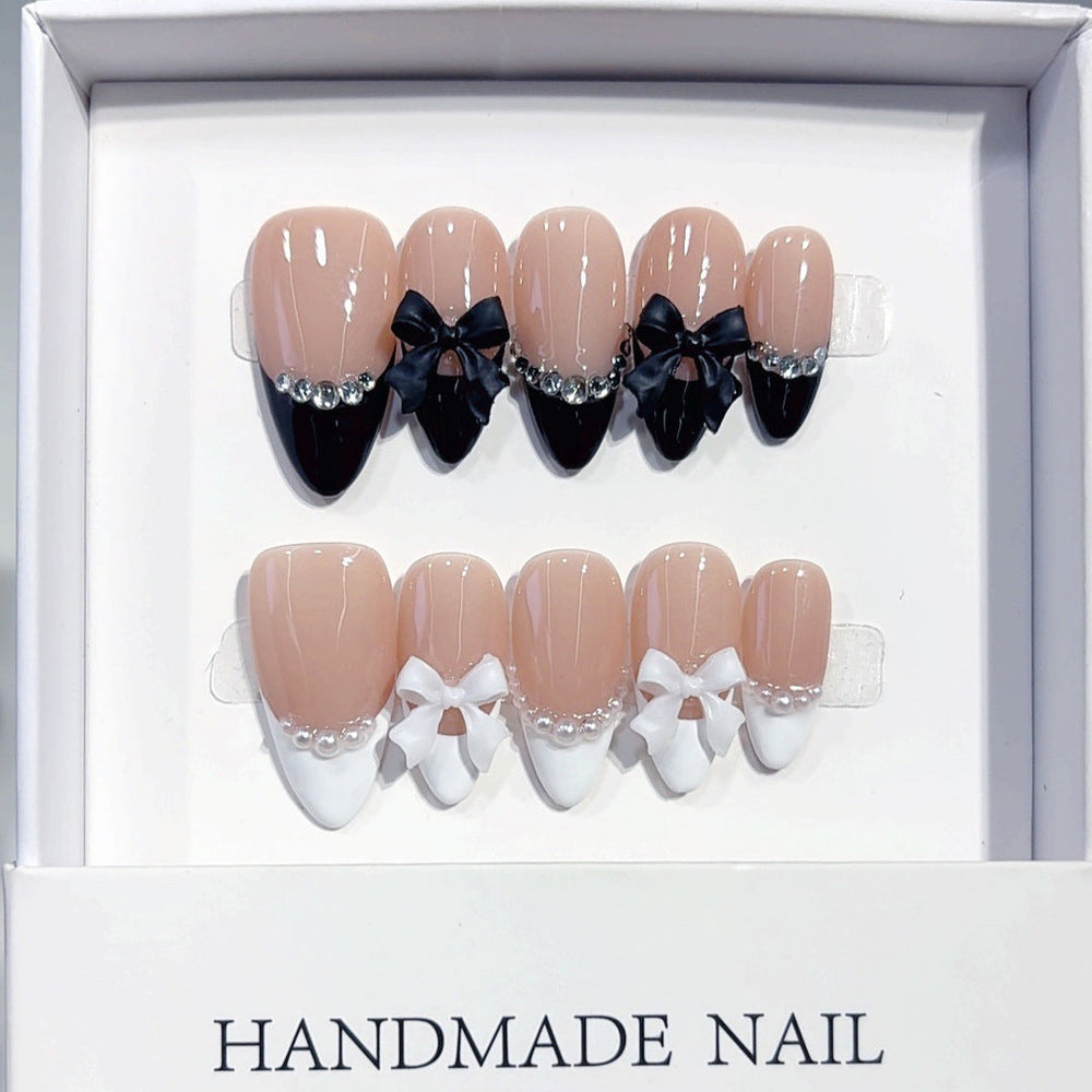 Black and white French almond press-on nails with a bow accent, used as a design reference for custom ODM press-on nail briefs.