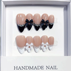 Black and white French almond press-on nails with a bow accent, used as a design reference for custom ODM press-on nail briefs.