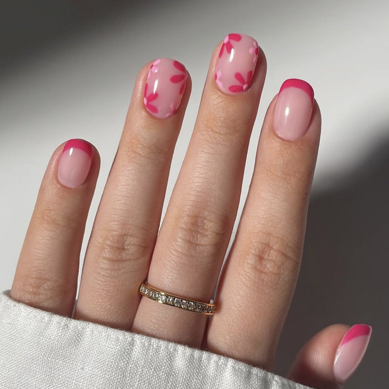 Simple French red press-on nails on short square manicure pieces with fresh flower accent, representing a quality control sample for supplier comparison