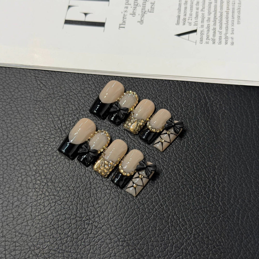 Custom press-on nails featuring 3D bowknot and gold foil on a short square base, illustrating the level of detail achievable through ODM partnerships.