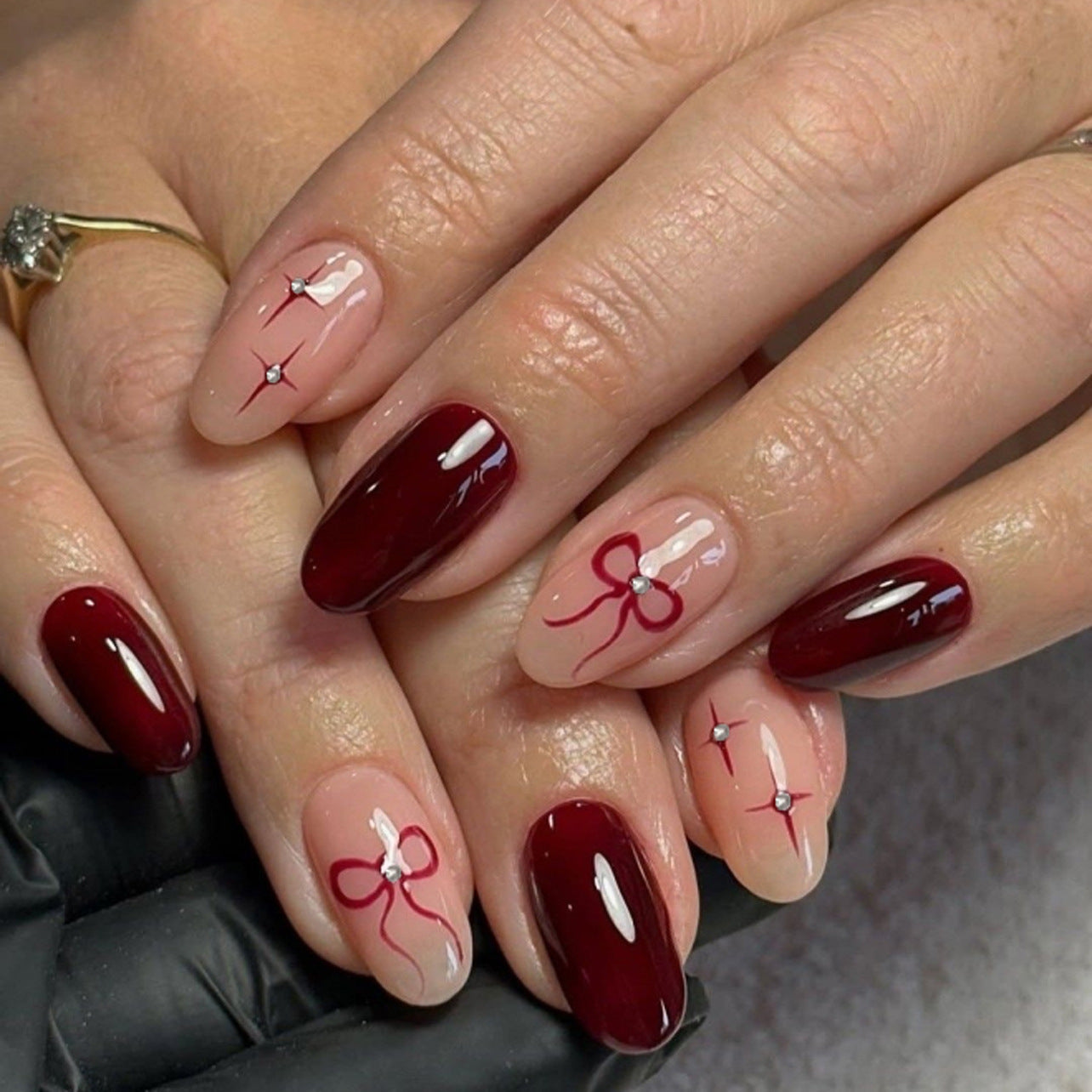 Private label press-on nail retail display showing curated starter assortment of Elegant Burgundy Bow Accent Oval Press On Nails sets in branded packaging.