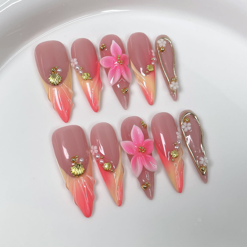 Assorted finished press-on nail set with coral, shell, and gold accents arranged on a neutral background, designed for wholesale buyers.