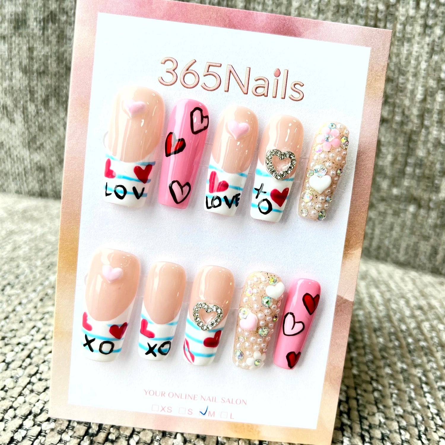Flatlay close-up showing labeled press-on nail sample cards in ABS, hard gel, and acrylic-resin with adhesive tabs, a small bottle of nail glue, and a sizing wheel on a neutral background.