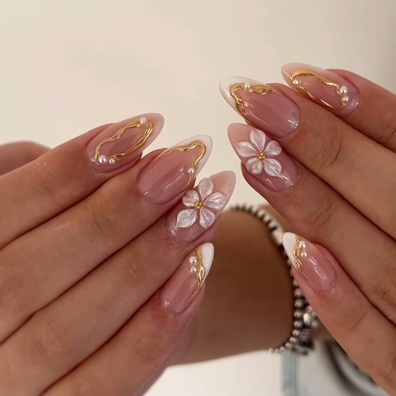 Elegant nude French tip press-on nails with 3D floral and pearl accents, perfect for salon retail inventory.