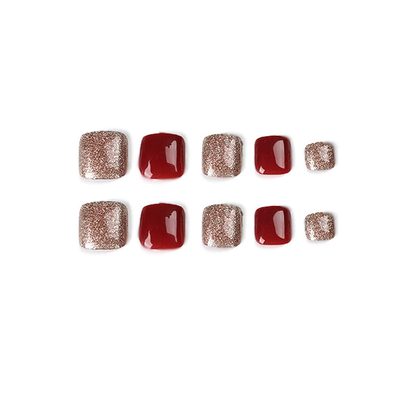 Ten red and gold glitter press-on toenails arranged in two rows.