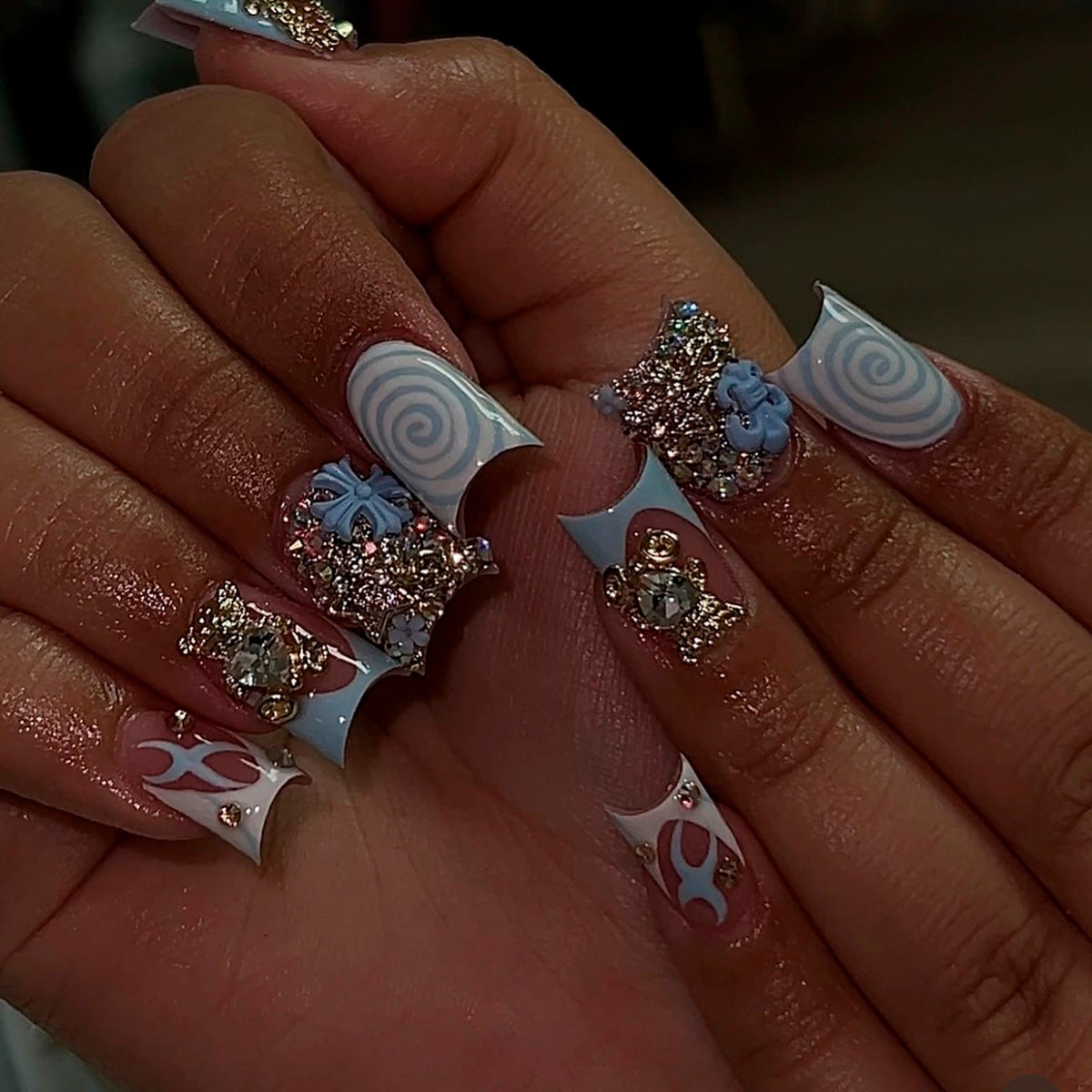 Hand wearing long blue and nude press-on nails with rhinestones