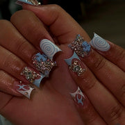 Hand wearing long blue and nude press-on nails with rhinestones