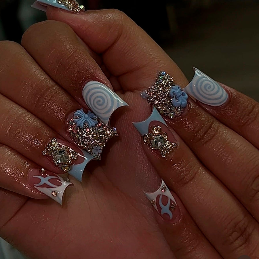 Hand wearing long blue and nude press-on nails with rhinestones