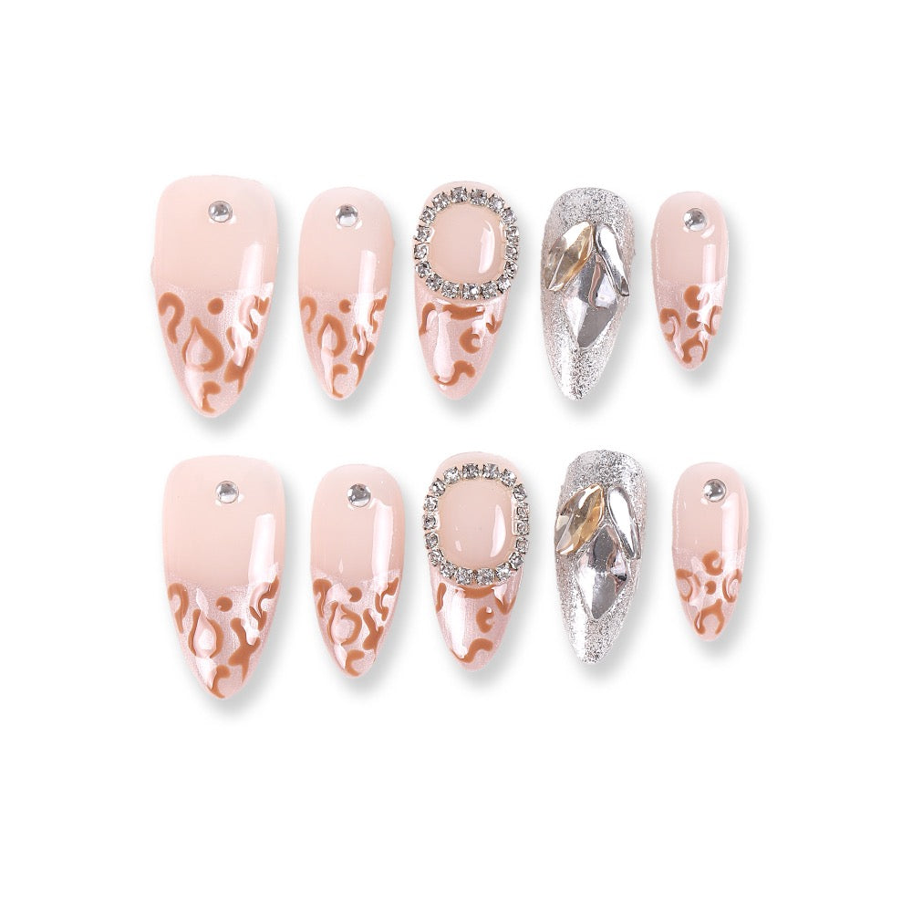 Uñas postizas 365Nails color nude almendra con diseño francés de leopardo y pedrería.