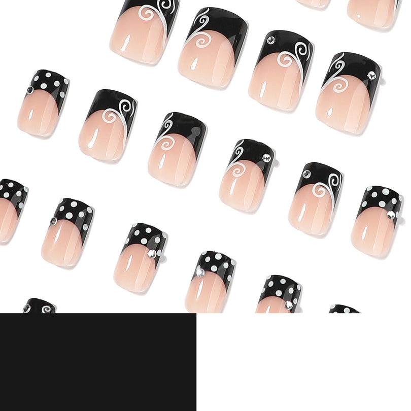 Scattered view of black french tip square press-on nails with white polka dots and swirl accents