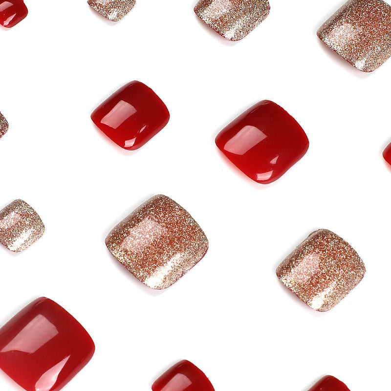 Close-up of glossy red and gold glitter square press-on toenails.