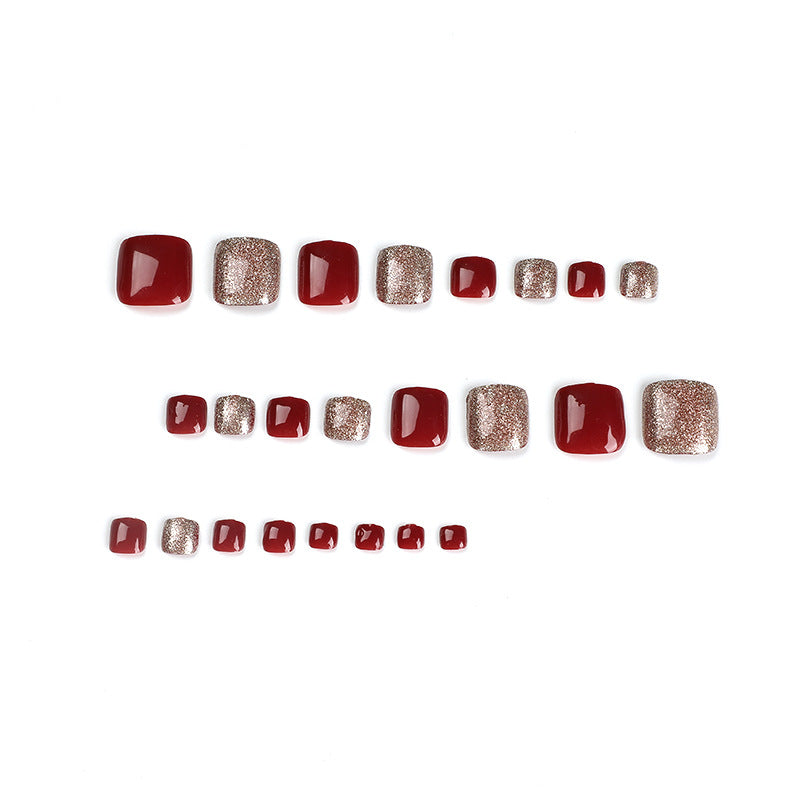 Twenty-four red and gold glitter press-on toenails arranged in rows.
