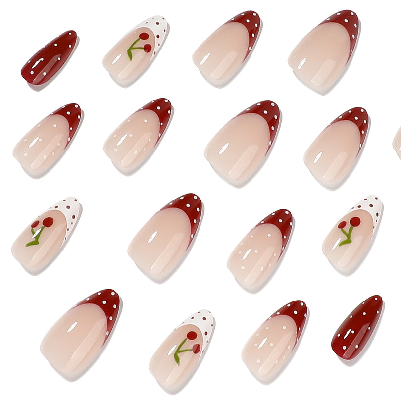 Close-up of glossy almond press-on nails with cherry motifs and dotted tips