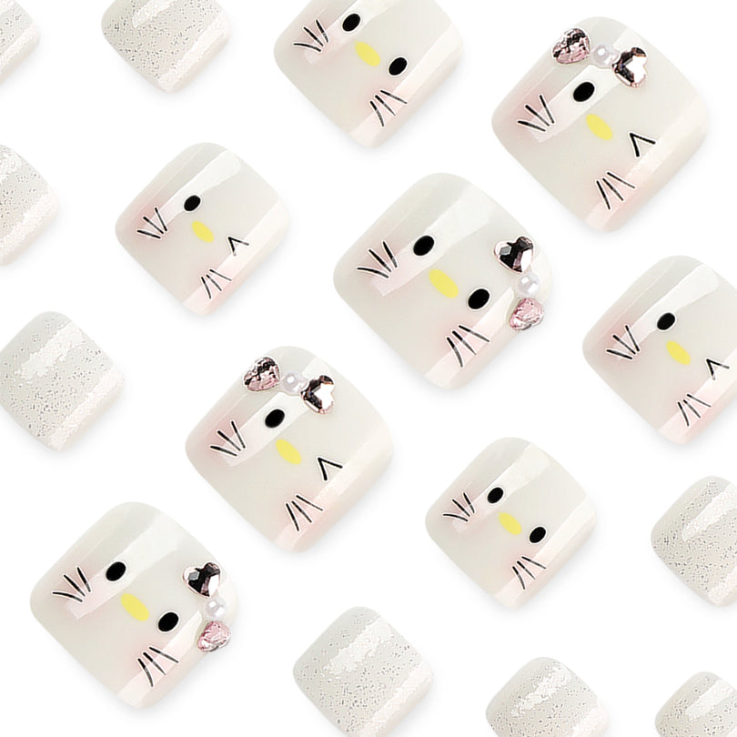Close-up of cat-face press-on toenails with pink bow details and silver glitter nails.