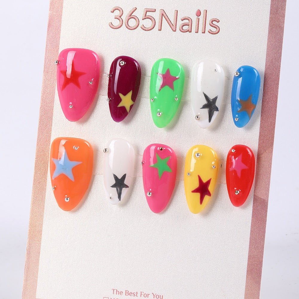 Uñas postizas largas de almendra neón de 365Nails con calcomanías de estrellas y tachuelas.