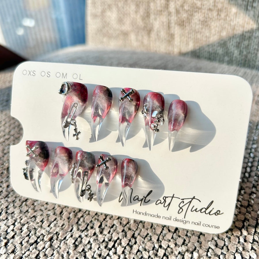 Ongles press-on griffe gothique vortex de minuit — rouge‑noir transparent, forme stiletto avec breloques argentées