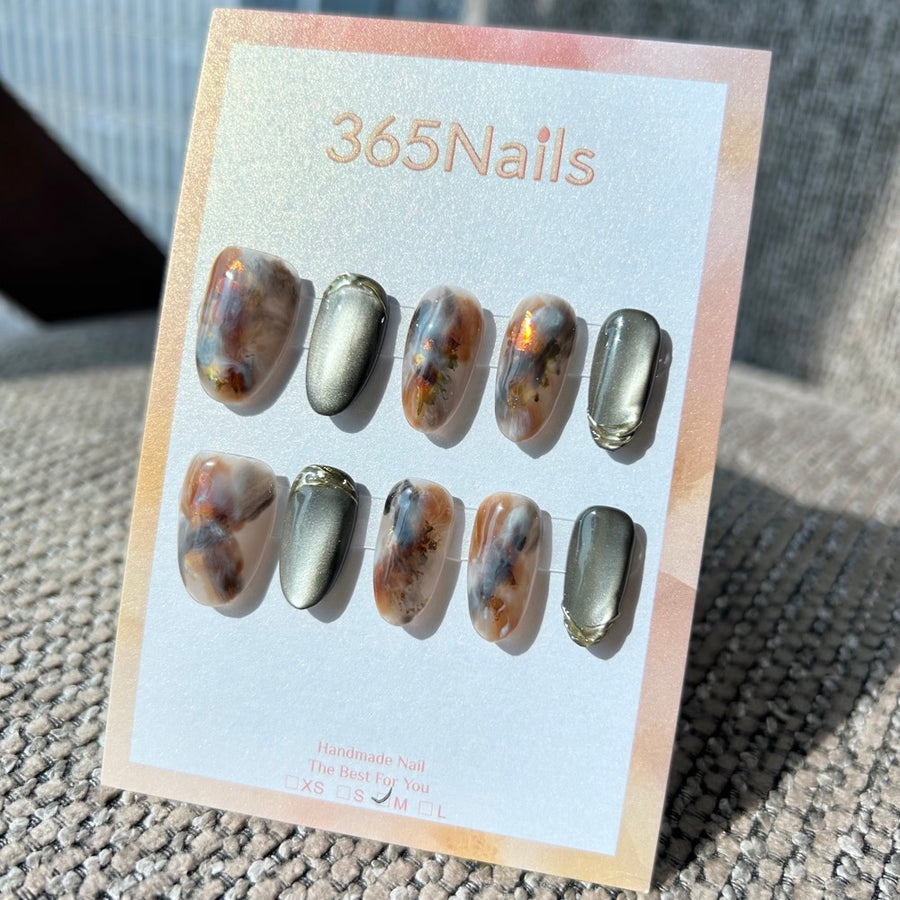 Ethereal Ink: "Gilded Olive Smoke" — ongles forme ovale effet œil-de-chat gris acier et marbré ambre‑bleu avec bordure chrome doré 3D