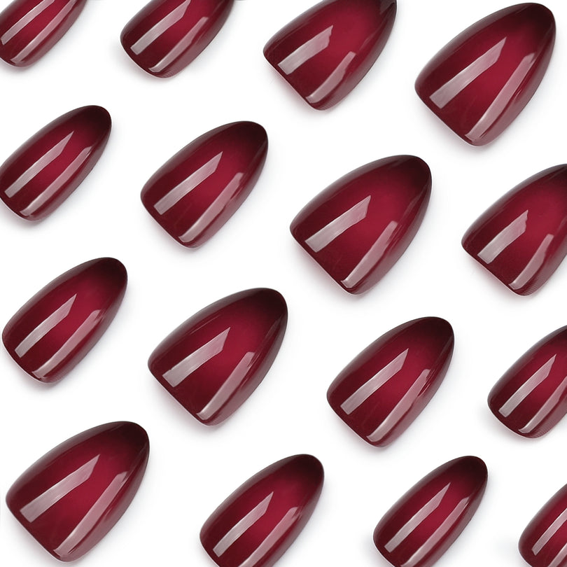 Close-up of glossy deep red press-on nail tips on white background