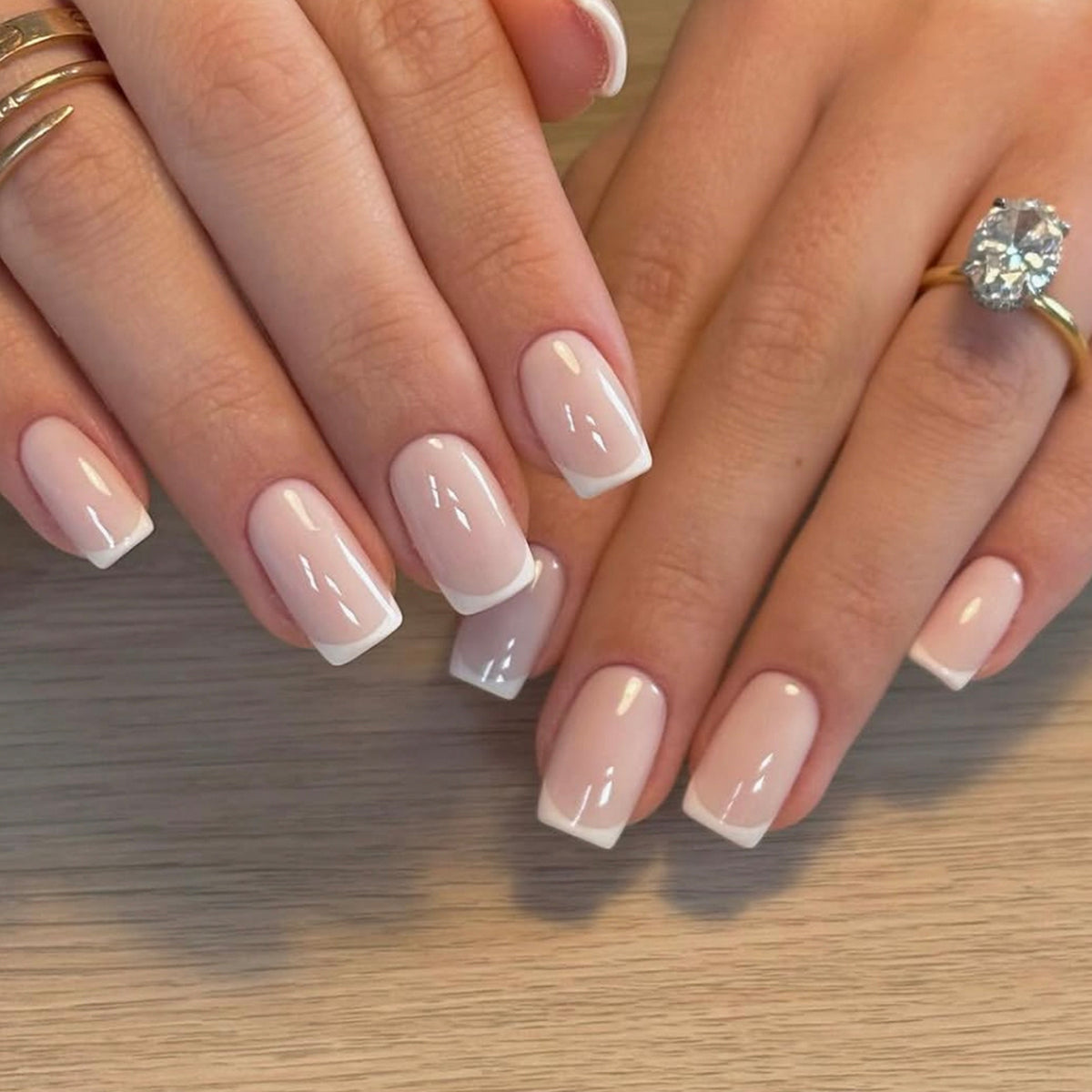 Hand wearing short pale pink French tip press-on nails