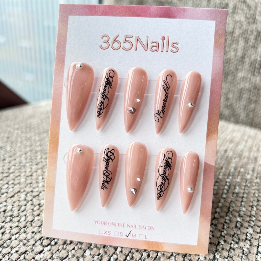 Femme Fatale: Écriture gothique — base nude rosé avec lettrage Old English noir et clous argentés — ongles press-on longs forme stiletto