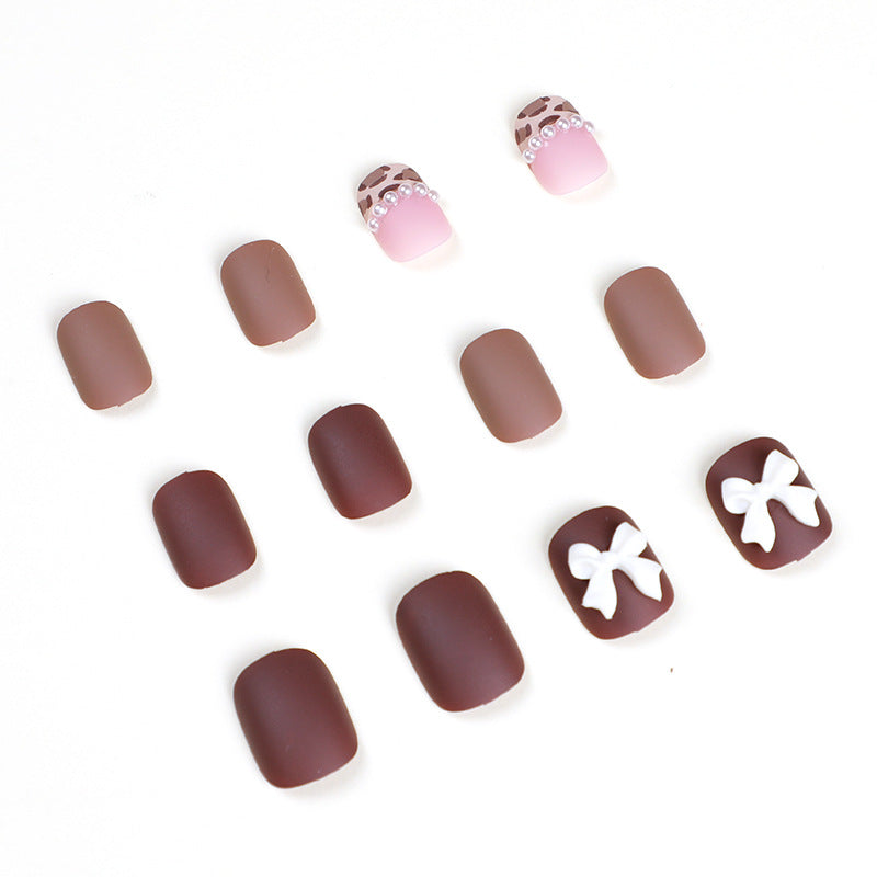 Set of press-on nails with white bow charms, pearls and pink tips on white background