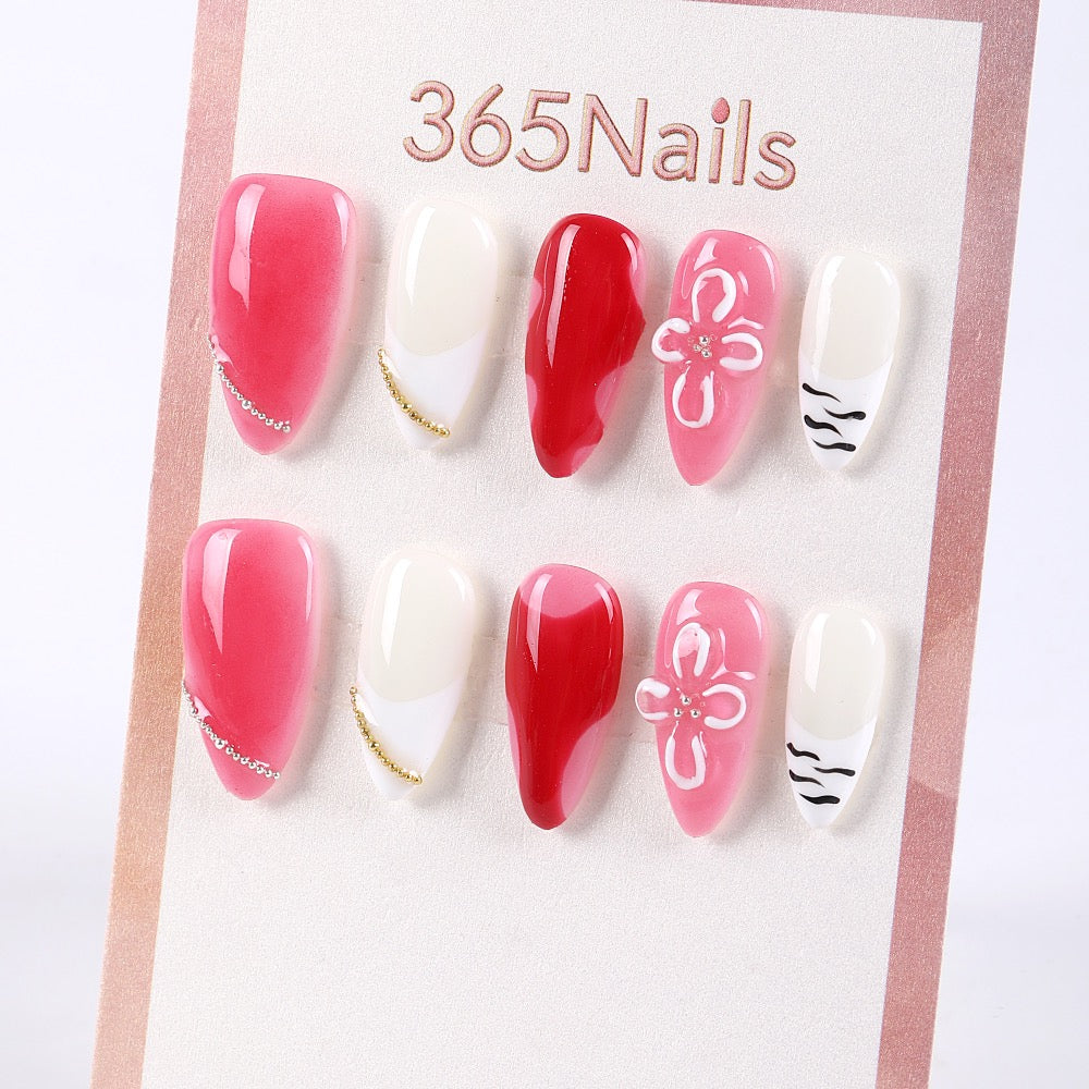 Uñas postizas 365Nails rojas estilo francés con cerezas, flores 3D y cadena dorada.