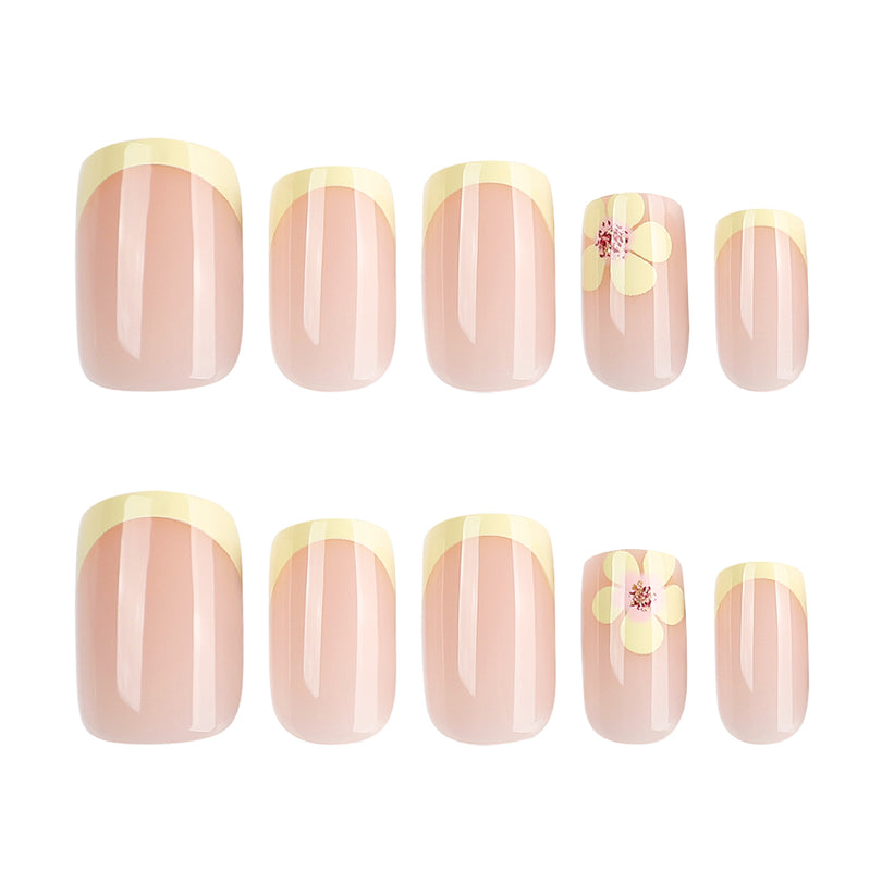 Five sizes of nude press-on nails with yellow french tips and one floral accent shown in two rows