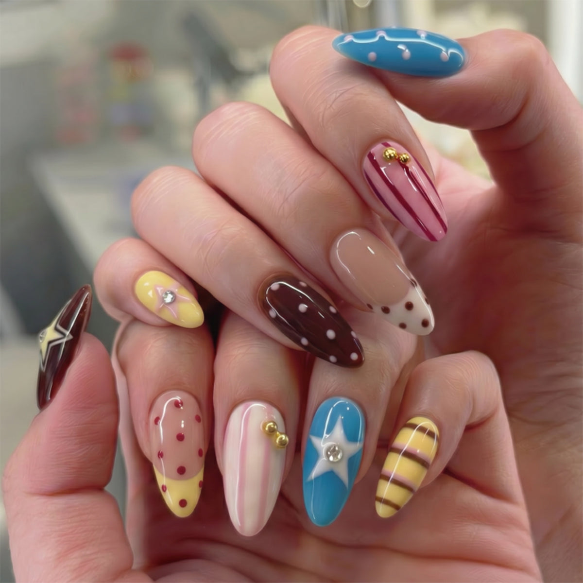 Hand modeling colorful almond press-on nails with stars and dots