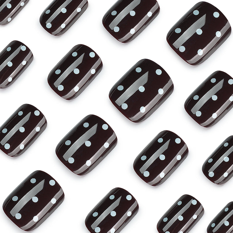 Close-up of glossy black square nails with white polka dots