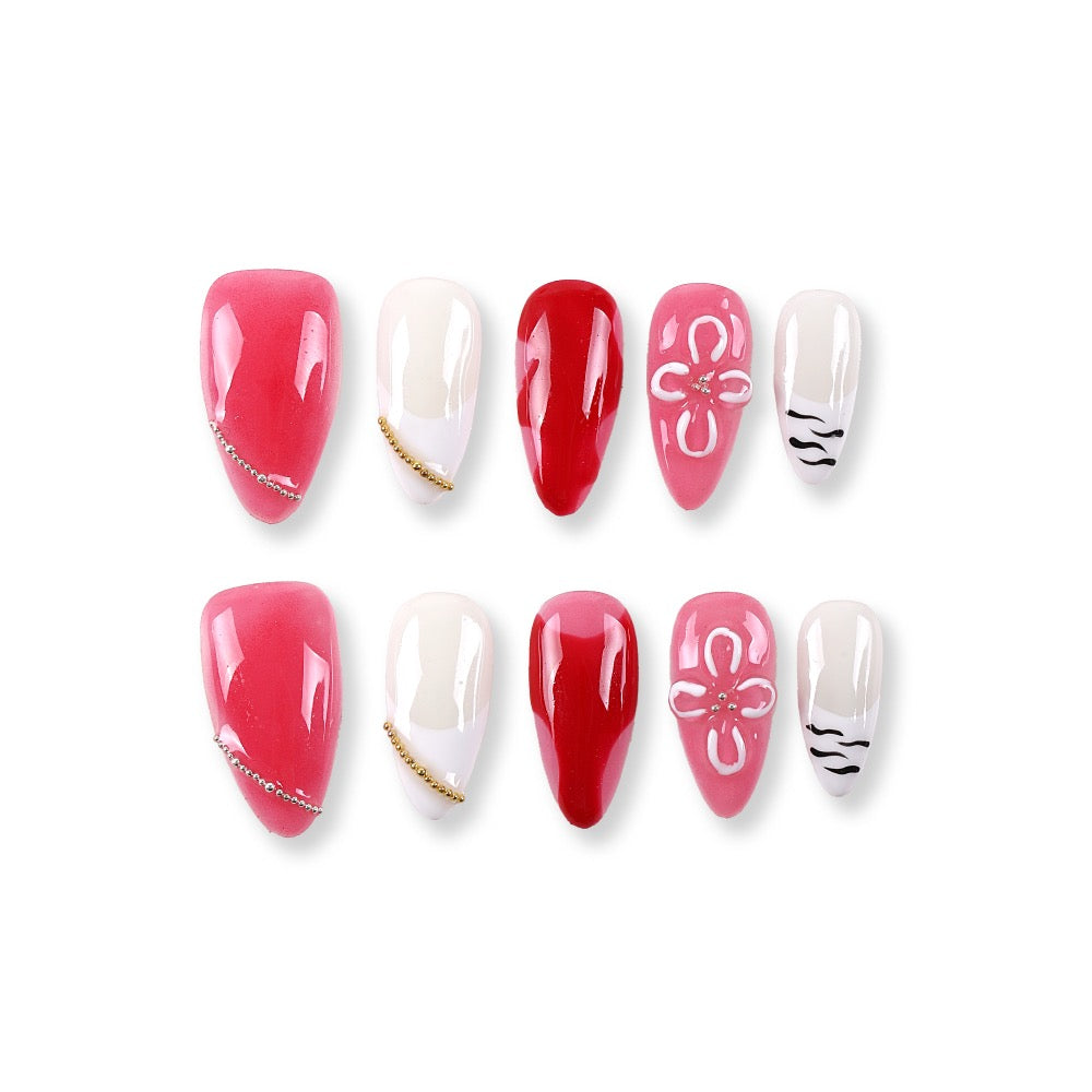 Uñas postizas 365Nails rojas estilo francés con cerezas, flores 3D y cadena dorada.