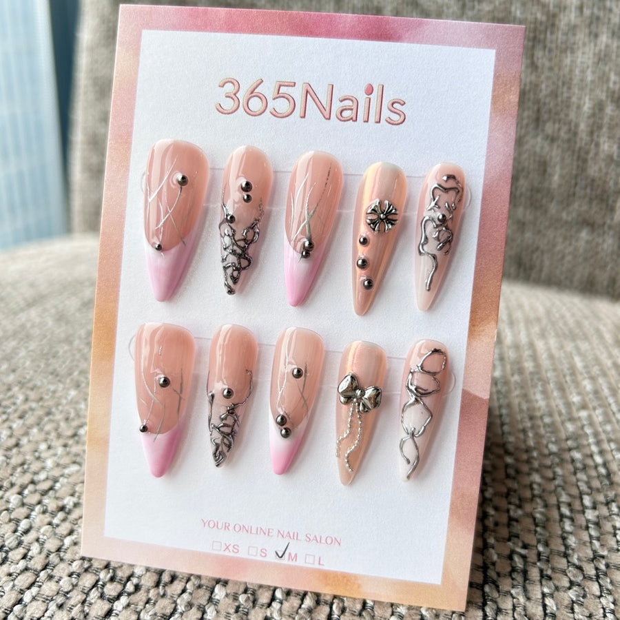 Femme Fatale : « Coquette cybernétique » – base ombré rose nude avec lignes argent liquide, breloques nœud métal et chaîne — ongles press-on longs forme amande