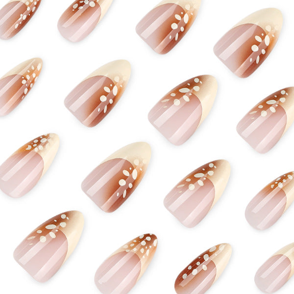 Close-up of almond nails with brown ombre tips and scattered white speckles