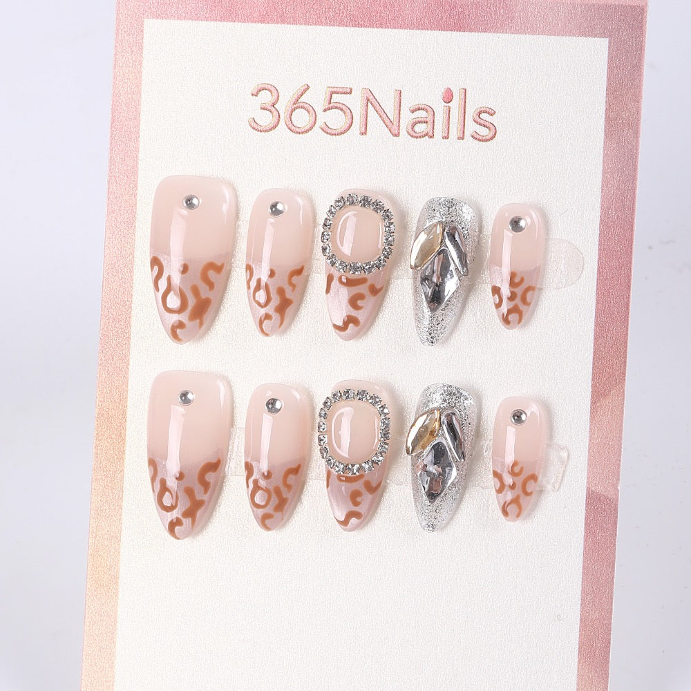 Uñas postizas 365Nails color nude almendra con diseño francés de leopardo y pedrería.