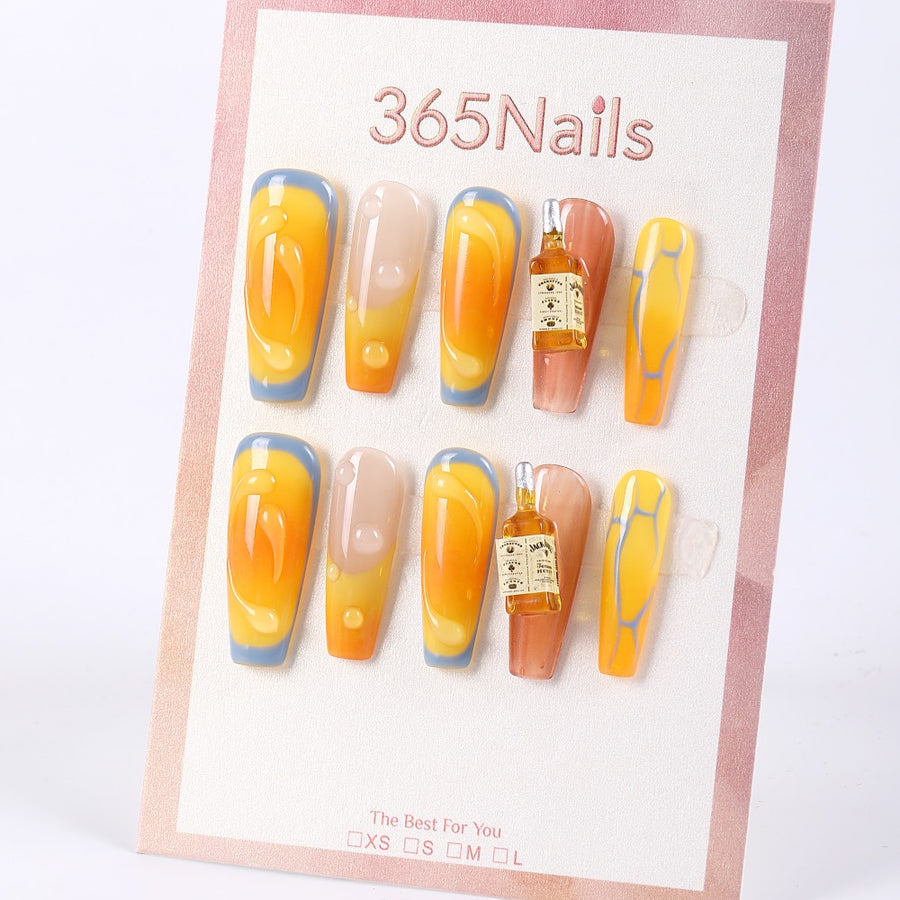 Uñas postizas largas de color ámbar miel 365Nails con forma de ataúd, gotas de rocío en 3D y dijes de mini botellas.