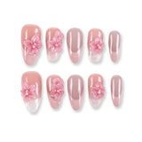 Uñas postizas almendradas largas 365Nails color pétalo de rubor con flores 3D y purpurina azucarada.