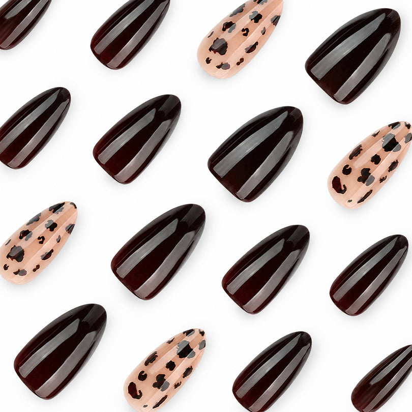 Close-up of glossy dark brown and nude leopard print almond nail tips arranged on white