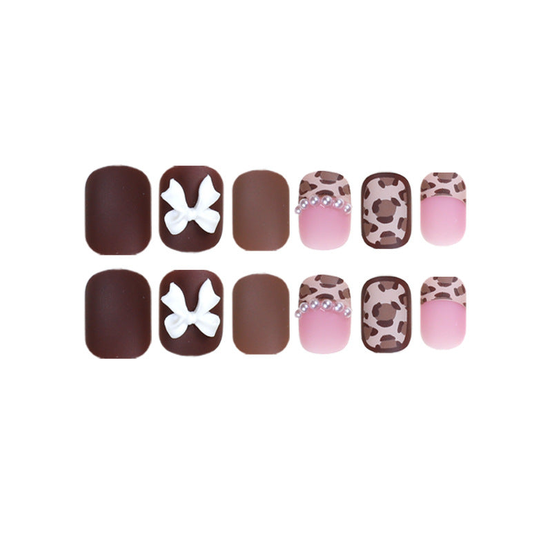 Full 12-piece press-on nail set arranged in two rows with bows, pearls and leopard print
